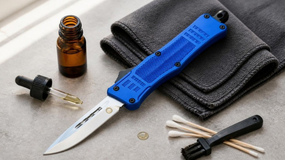 Blue OTF automatic knife with satin drop point blade beside a microfiber cloth, oil dropper, cotton swabs and a small brush