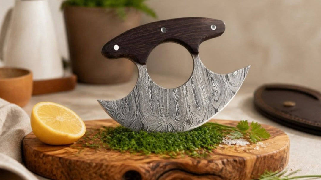 Damascus ulu knife with wenge wood handle rocking over freshly minced herbs on an olive wood board